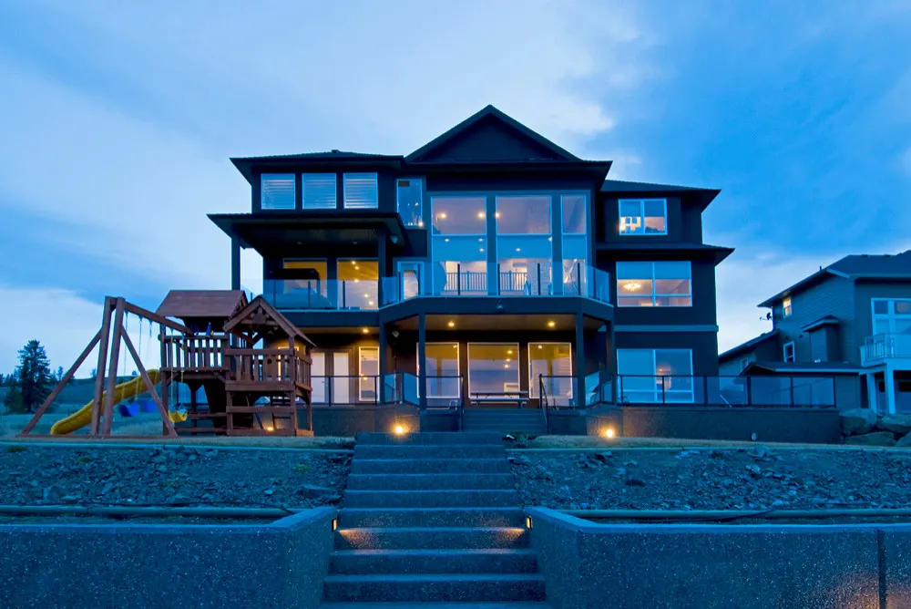 Rear elevation of the Telford custom home at dusk, three storeys of view decks